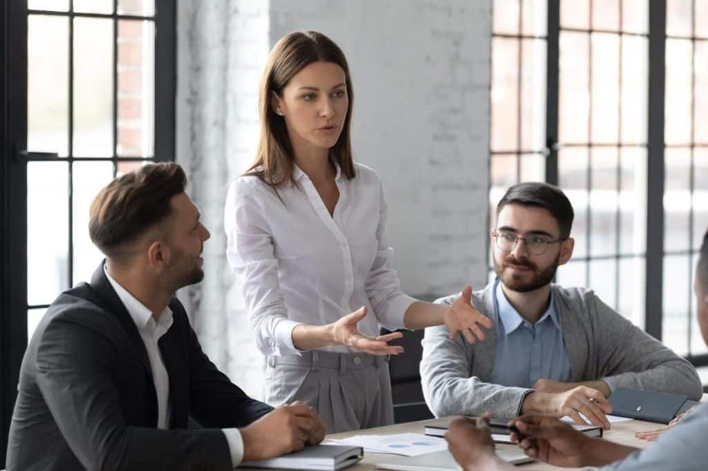 Jeune étudiante en formation marketing numérique travaillant avec une équipe de consultants en marketing