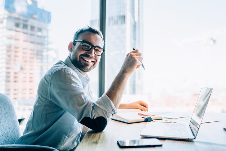 A smiling digital marketing professional in a home office after completing a digital marketing course online