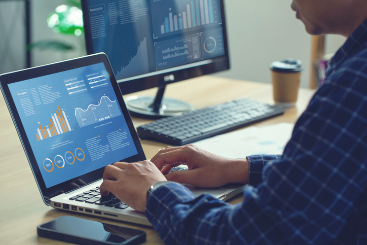 A digital marketer analyzing data on a laptop with charts and graphs displayed on the screen after completing his digital marketing diploma program