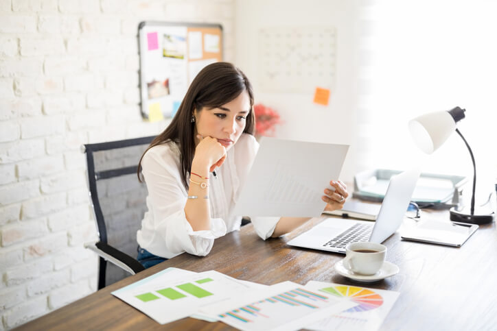 A marketing professional reviewing reports labelled with their agency’s logo after completing her diploma in digital marketing