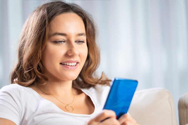 Smiling female digital marketing professional watching short-form video marketing content on a phone.