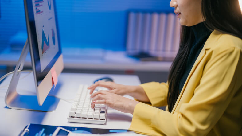 A digital marketing strategist typing on a keyboard while planning a digital marketing campaign.